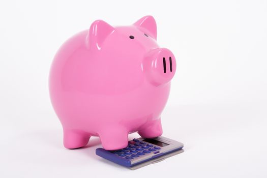 Pink piggy bank on the calculator, isolated on white background.