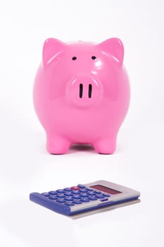 Pink piggy bank near calculator, isolated on white background.