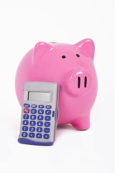 Calculator leans to pink piggy bank, isolated on white background.