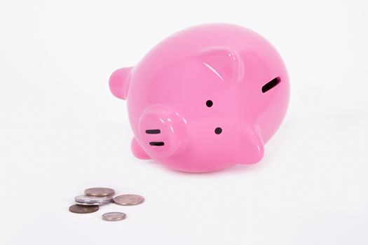 Pink piggy bank falls and coins on the ground, isolated on white background.