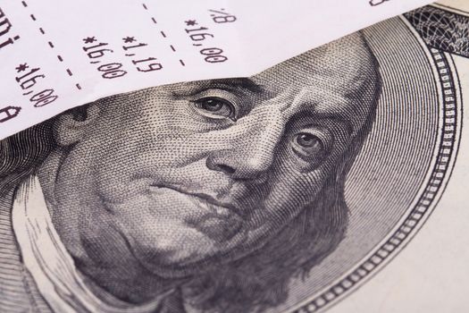 Macro view of cash register receipt and one hundred dollar bill.