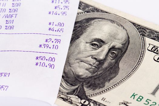Macro view of cash register receipt and one hundred dollar bill.