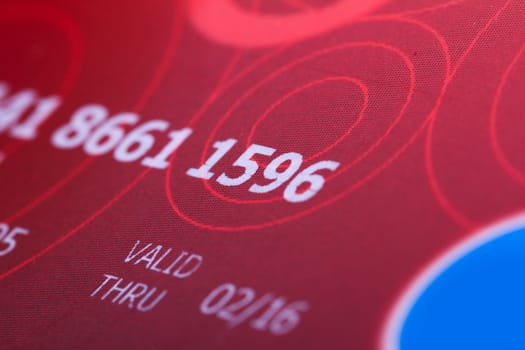 Close up of red credit card for shopping with numbers.