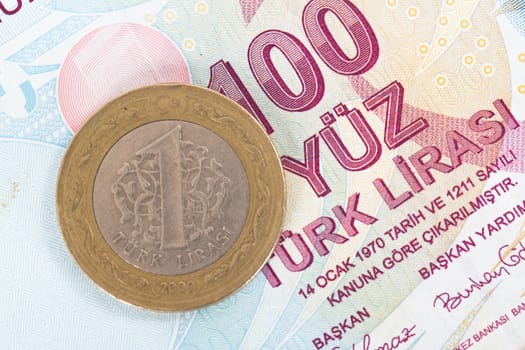 One Turkish lira coin on one hundred banknote.