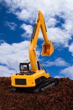 Construction machine, excavator on pile of soil digging a trench, cloudy sky background.