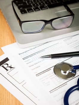 Prescription form with pen stethoscope and laptop computer