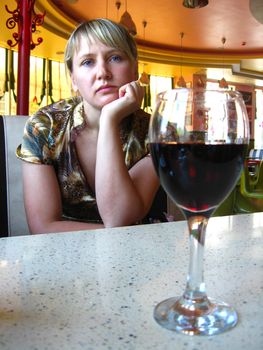 lonely and sad girl with glass of red wine in restaurant