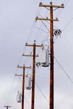 Row utility poles hung with electricity power cables and transformers for residential electric power supply