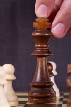 Businessman playing chess and holding king chess piece on board.