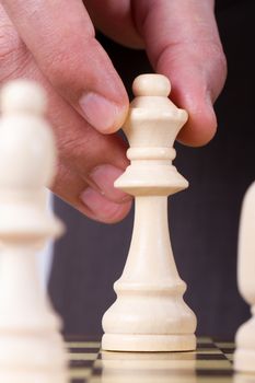 Businessman playing chess and holding queen chess piece.