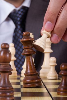 Businessman holding pawn, hitting and defeating opponent king on chess board.