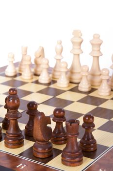 Chess board with starting positions aligned chess pieces, isolated on white background.