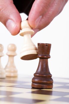Close up view of businessman holding pawn and defeating castle, isolated on white background.