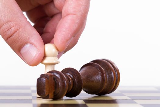 Victory concept, businessman holding pawn against king on chess board, isolated on white background.