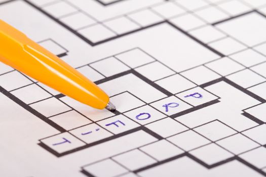 Close up of blank square crossword puzzle with pen and profit text.