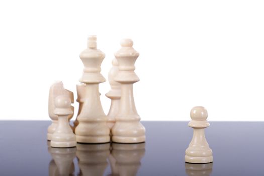 Single chess piece pawn standing out from the group on dark glass table, isolated on white background.