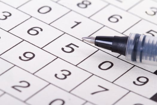 Close up of numbers crossword puzzle with black pen.