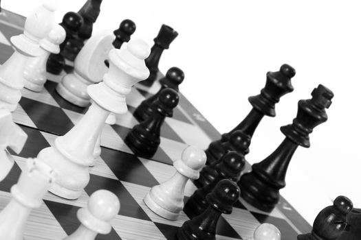 Black and white chess pieces on board, isolated on white background.