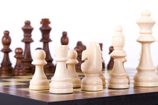 Chess board with chess pieces in a row, isolated on white background.