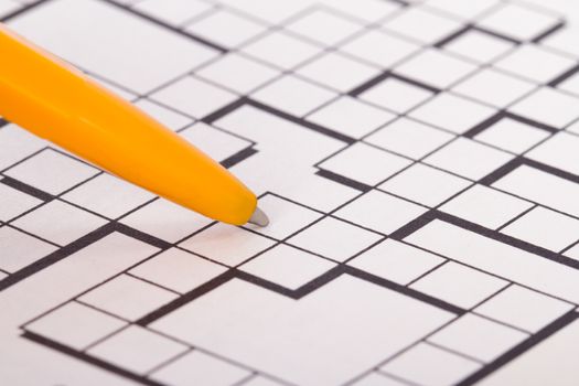 Close up of blank square crossword puzzle for solution with pen.