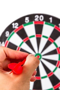Hand holding plastic, red arrow and throwing to dart board, isolated on white background.
