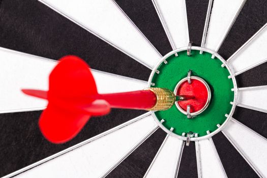 Red, plastic arrow hits center of dart board.