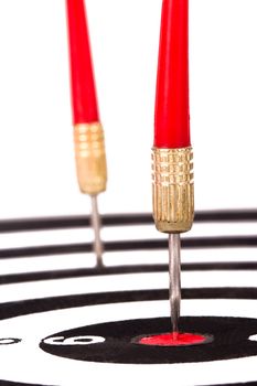 Red, plastic arrow hits middle of dart board, isolated on white background.