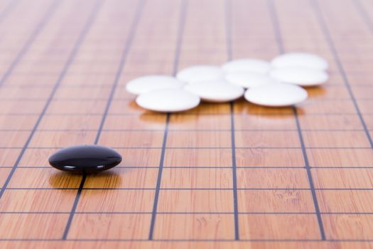 Black stone standing out from white pieces on Chinese go game board.