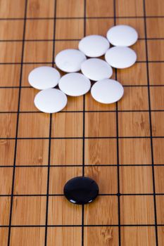 Black stone standing out from white pieces on Chinese go game board.
