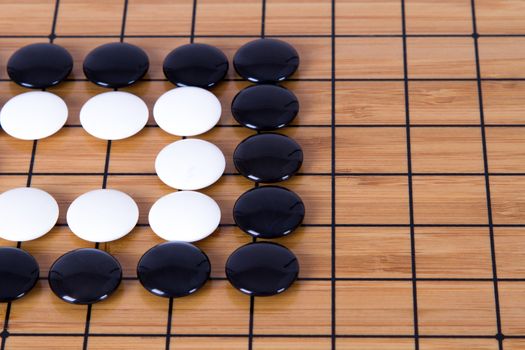 Close up view of black and white stone pieces on Chinese go game board.