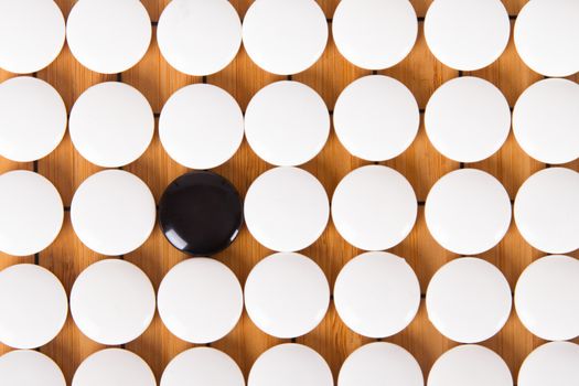 Black stone standing out from white pieces on Chinese go game board.
