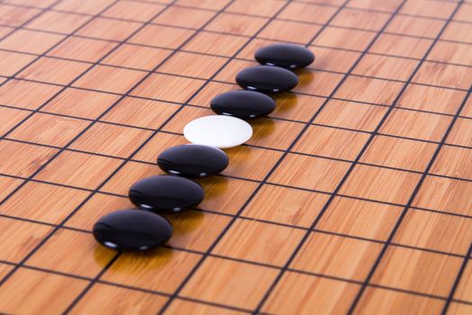 White stone standing out from blacks on Chinese go game board.