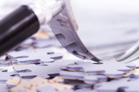 Close up of classic style magnifying glass and little puzzle pieces.
