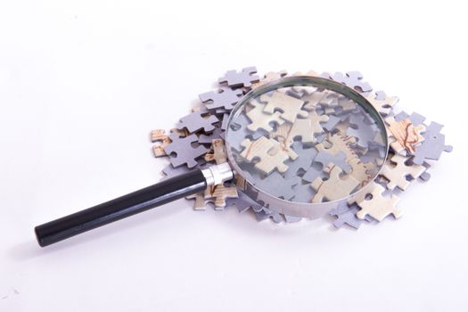 Classic style magnifying glass on little puzzle pieces, isolated on white background.
