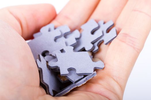Some little puzzle pieces in hand palm on white.
