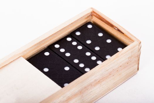 Black dominoes in wooden box, isolated on white background.