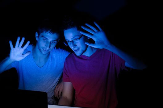 Two guys greeting someone through a video chat