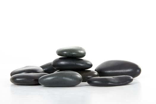 Black massage stones stacked, isolated on white background.