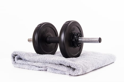 Black gym barbell, dumbbell with disks and blue towel, isolated on white background.