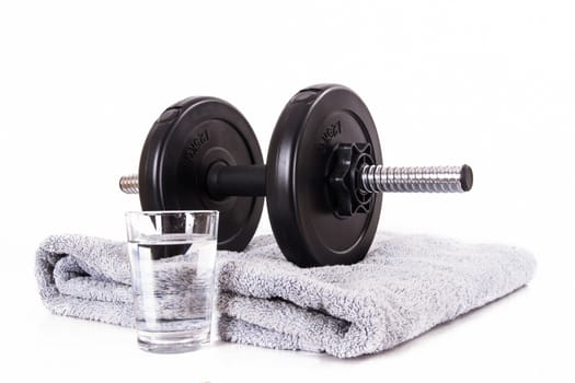 Black gym barbell, dumbbell with disks, blue towel and glass of water, isolated on white background.