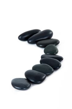 Black massage stones in a row, isolated on white background.