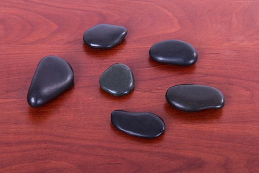 Black massage stones on wooden table.