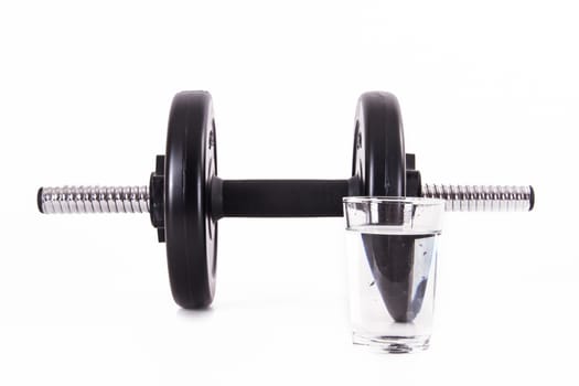 Black gym barbell, dumbbell with disks and glass of water, isolated on white background.