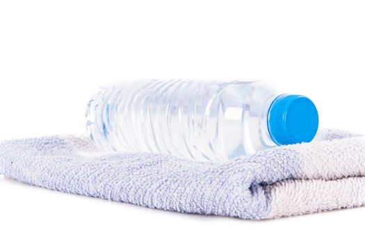Plastic water bottle on blue striped towel, isolated on white background.