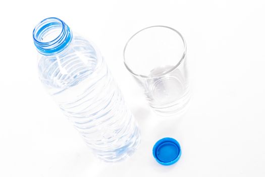 Plastic water bottle and glass, isolated on white background.