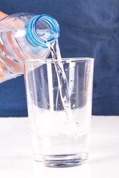 Pouring water into glass from plastic bottle.