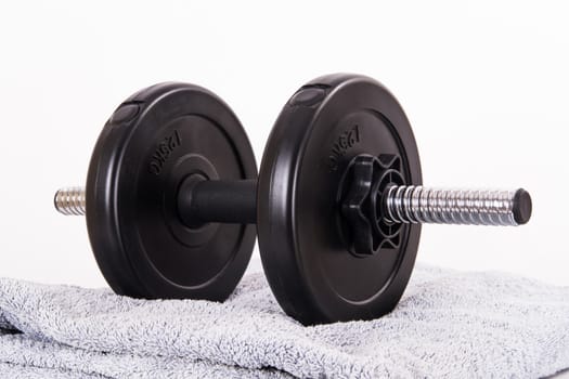 Black gym barbell, dumbbell with disks and blue towel, isolated on white background.