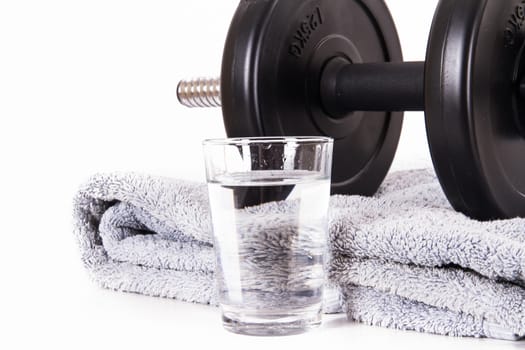 Black gym barbell, dumbbell with disks, blue towel and glass of water, isolated on white background.