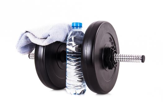 Black dumbbell with blue towel and plastic water bottle, isolated on white background.