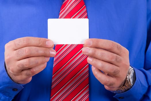 Businessman with red tie and blue shirt holding and showing blank, empty, white business card with two hands.